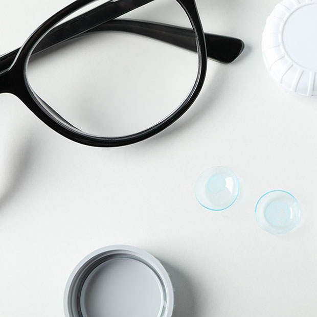 Glasses and contact lens case and solution on a white background