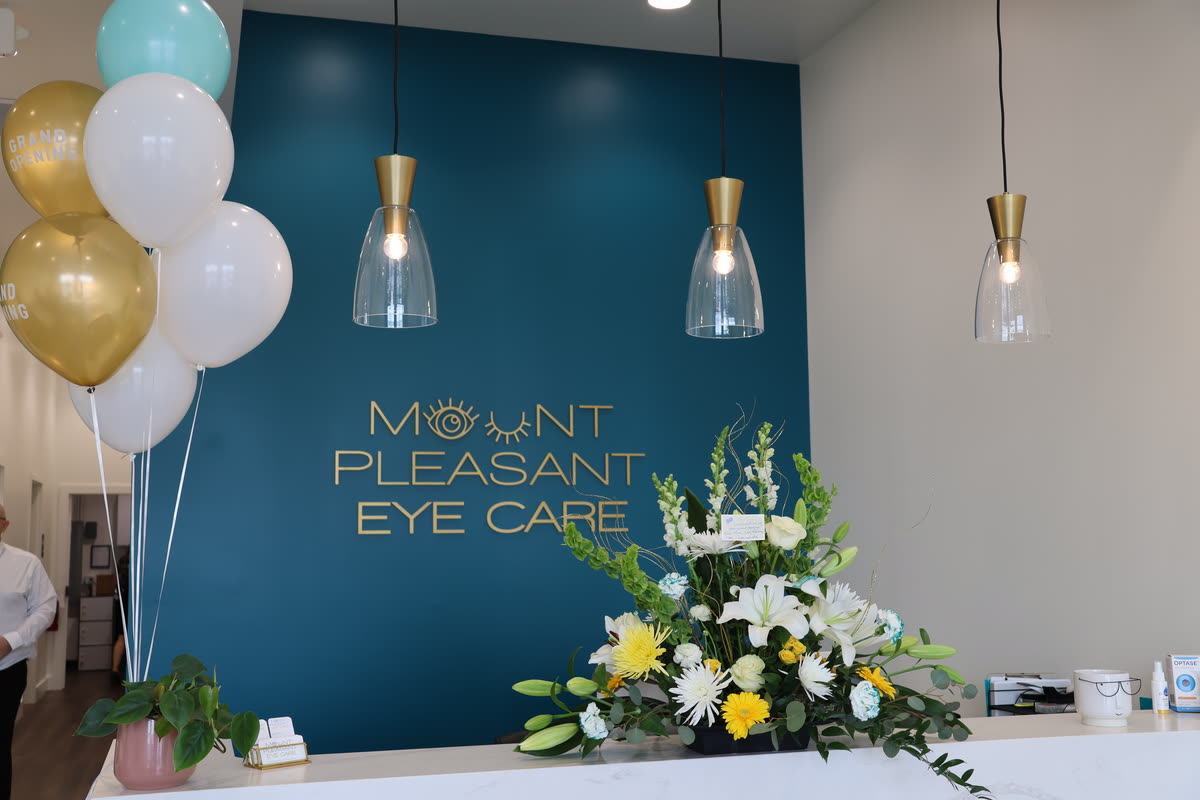 The finished front desk and teal logo wall, dressed with balloons and flowers on opening day