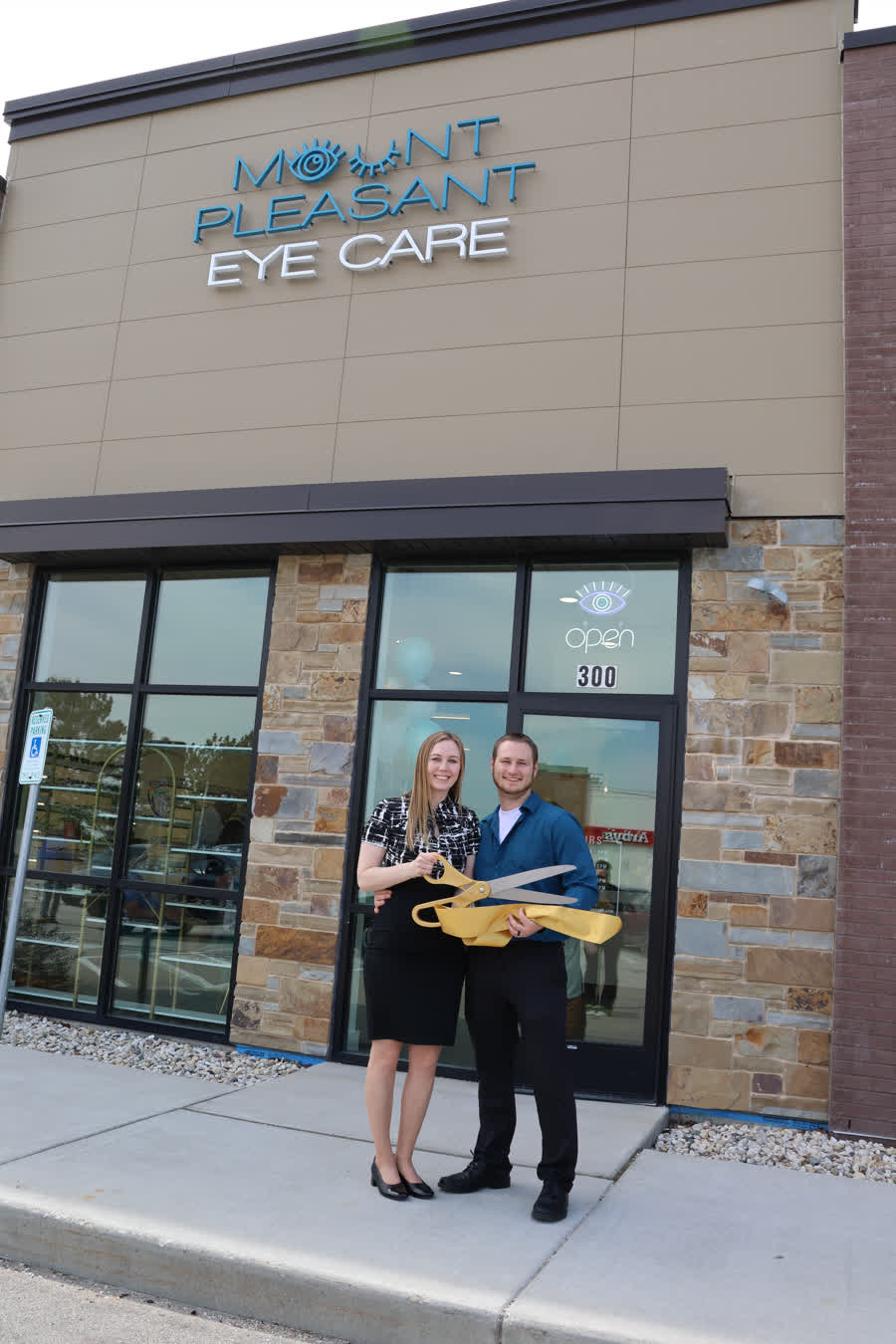 Katelyn and Devin Steen outside beneath the Mount Pleasant Eye Care storefront sign